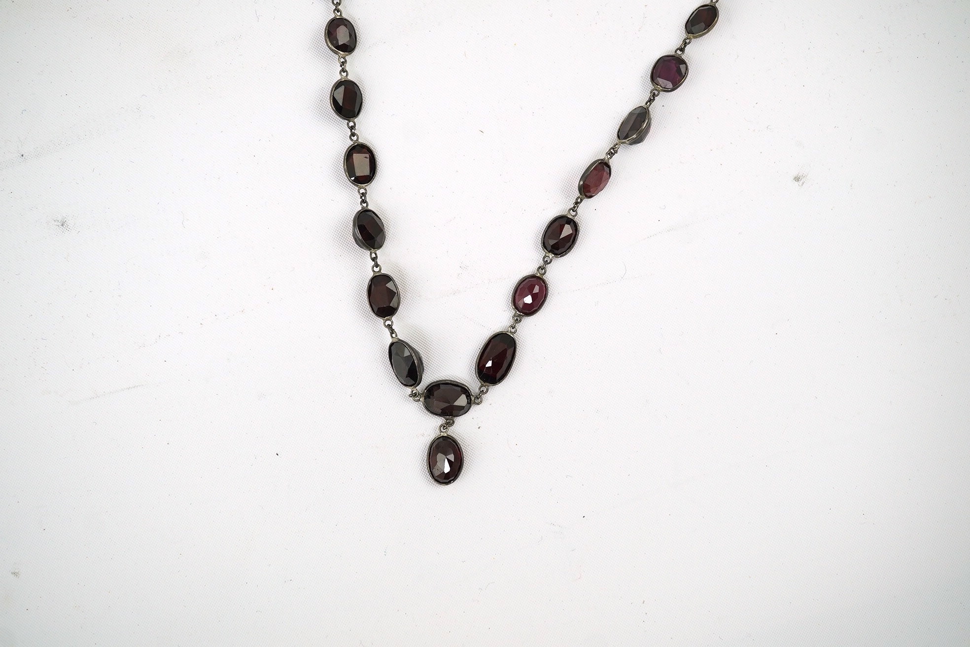 A Victorian silver and graduated oval cut two colour garnet set drop spectacle necklace, 74cm. Condition - poor to fair